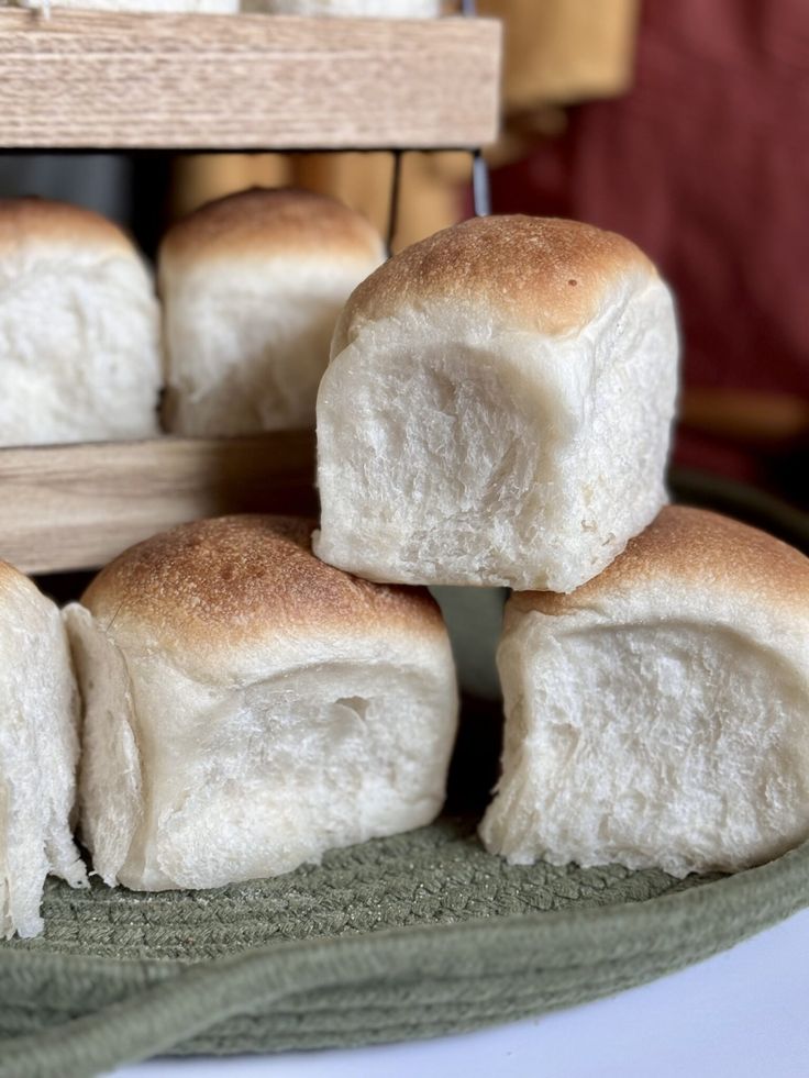 several rolls stacked on top of each other in front of a wooden rack filled with bread