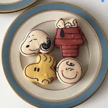 three cookies decorated to look like charlie brown and snoopy the dog on a plate