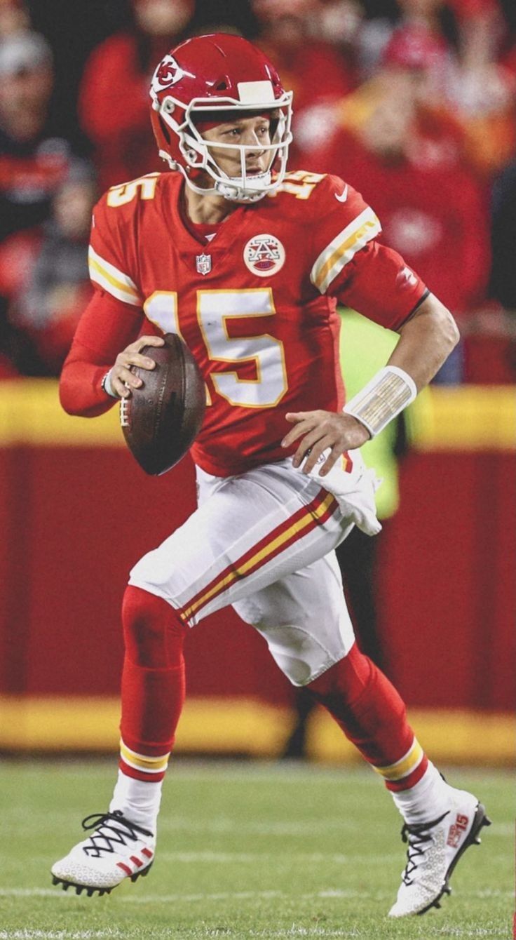 a football player is running with the ball in his hand and wearing a red uniform