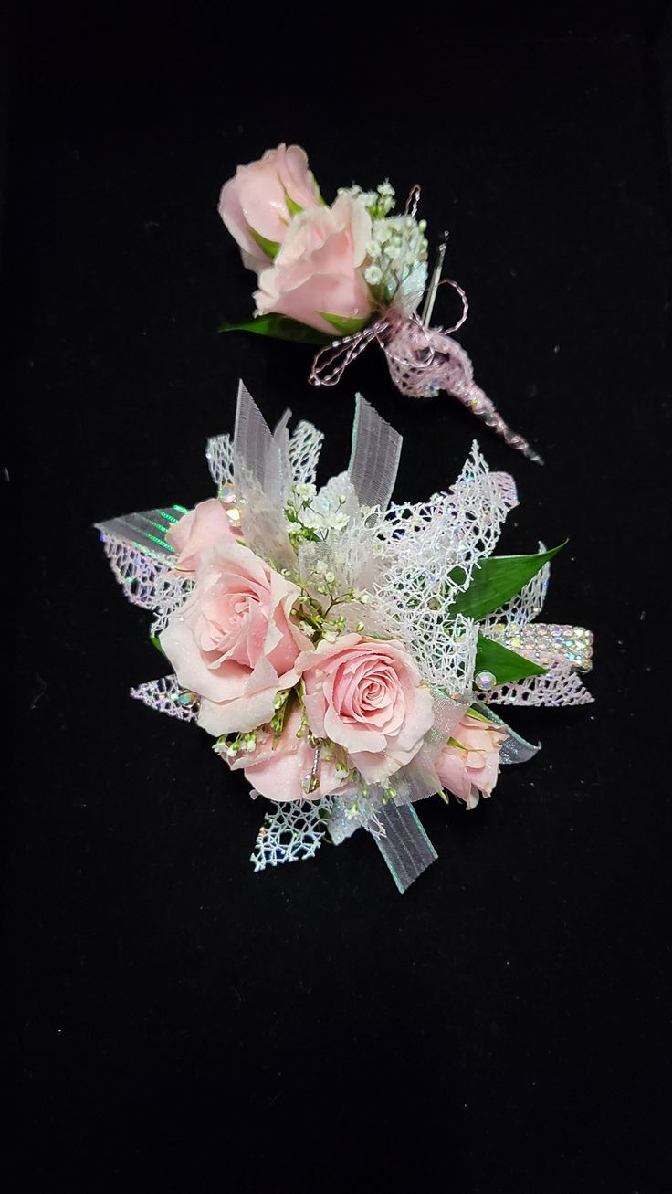 two bouquets of pink roses and white lace sit on a black surface, one with green leaves