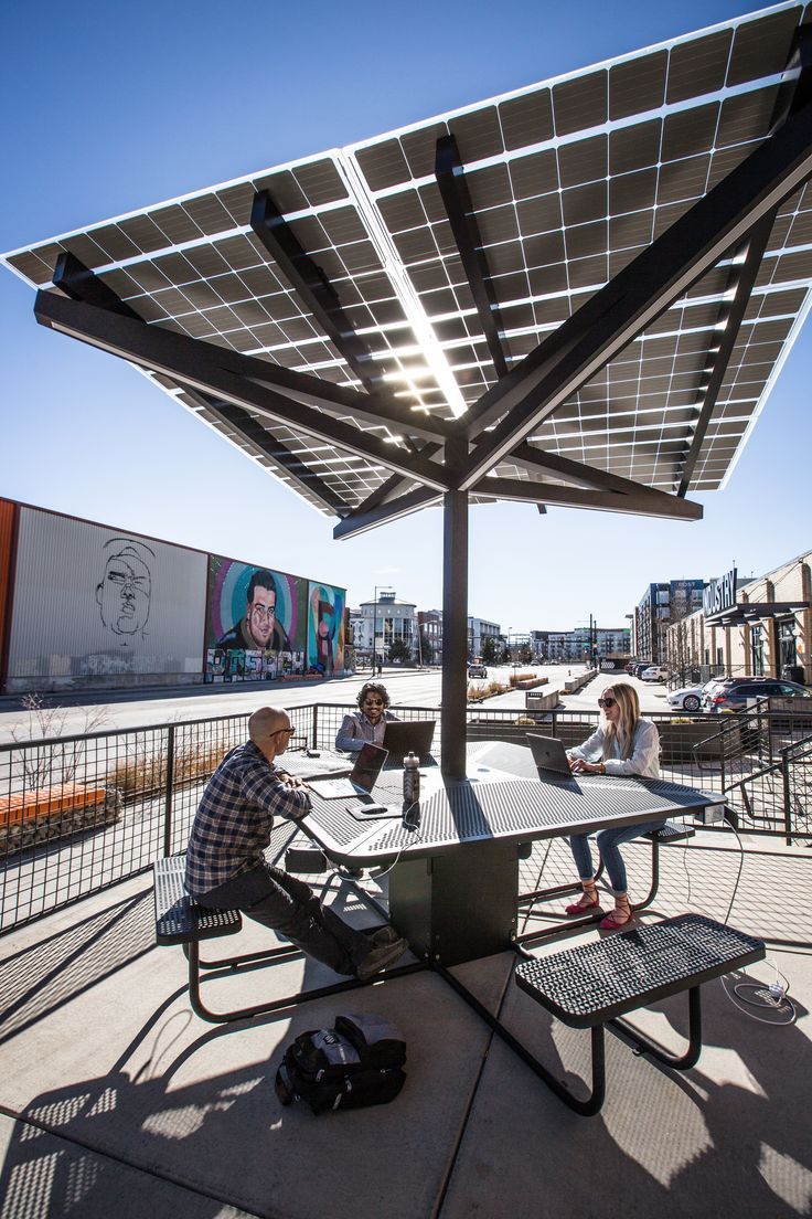 three people sitting at a table under a solar panel