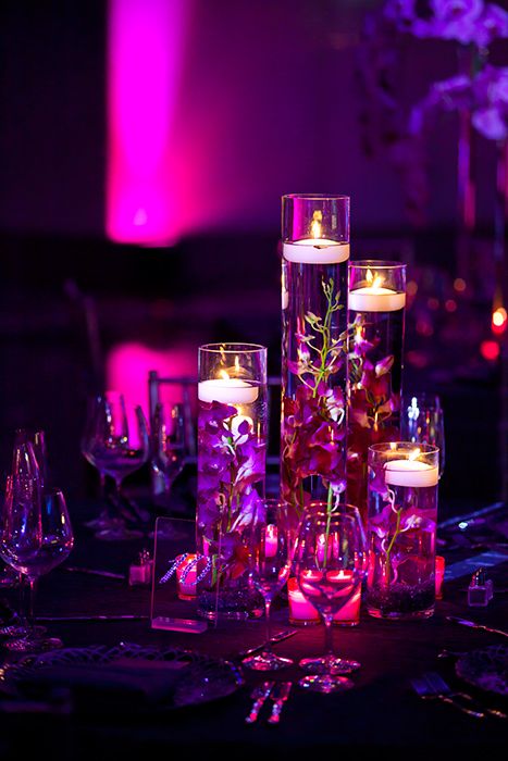 the centerpieces are filled with candles and flowers in glass vases on the table