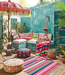 an outdoor living room with lots of colorful furniture and plants on the floor next to it