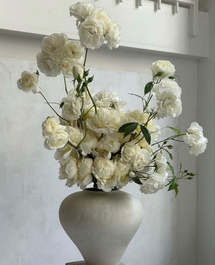 a white vase filled with lots of white flowers