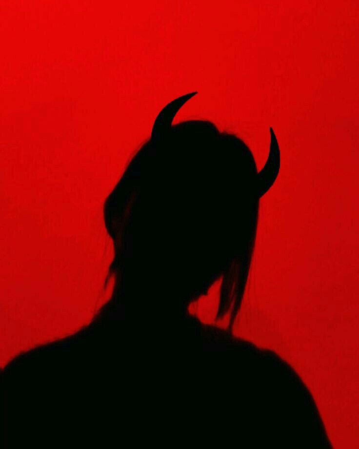 the silhouette of a person with horns on their head and long hair, against a red background