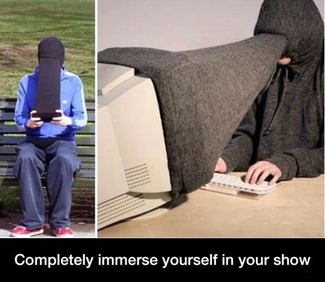 a person in a hooded jacket typing on a computer with a blanket over their head