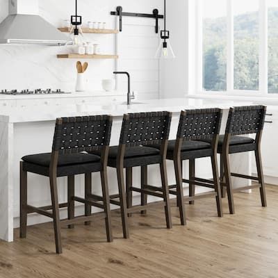 a kitchen with white walls and wooden floors has black chairs in front of the counter