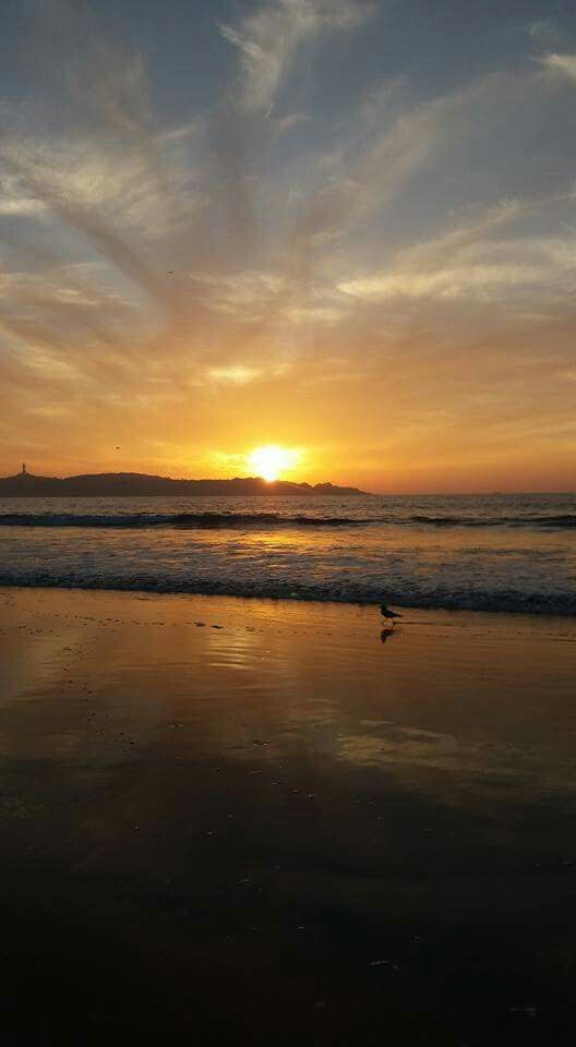 the sun is setting over the water at the beach