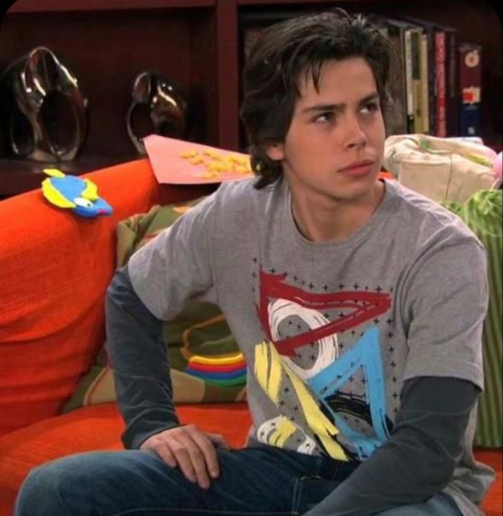 a young man sitting on top of a couch in front of a bookshelf