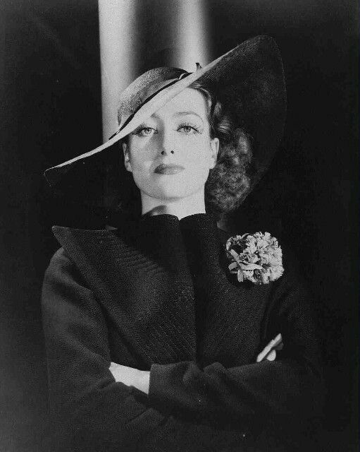 black and white photo of woman in hat with arms crossed, looking to the side