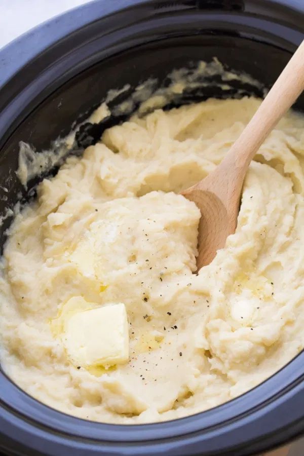 mashed potatoes in a crock pot with a wooden spoon and text overlay that reads easy crock pot mashed potatoes