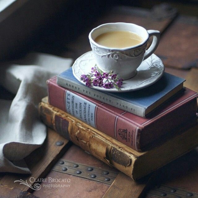 a stack of books with a cup of coffee on top