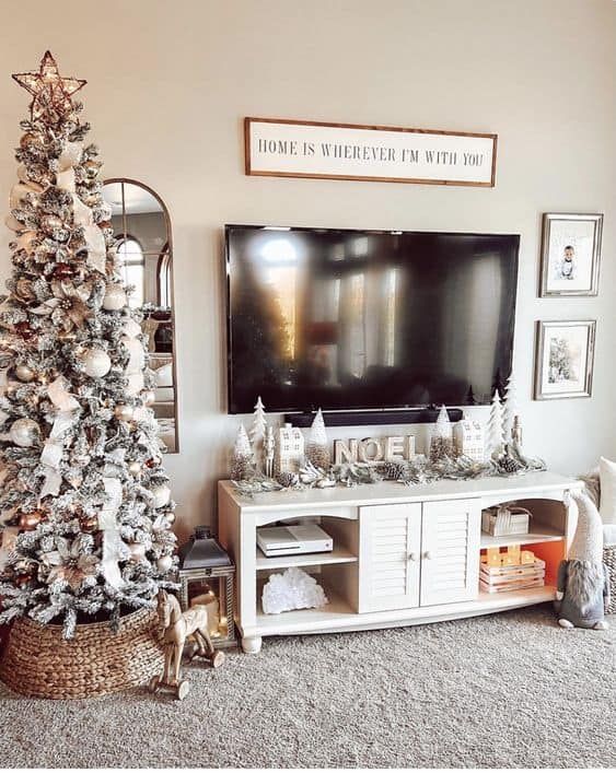 a living room decorated for christmas with a tv on the wall and a tree in front of it