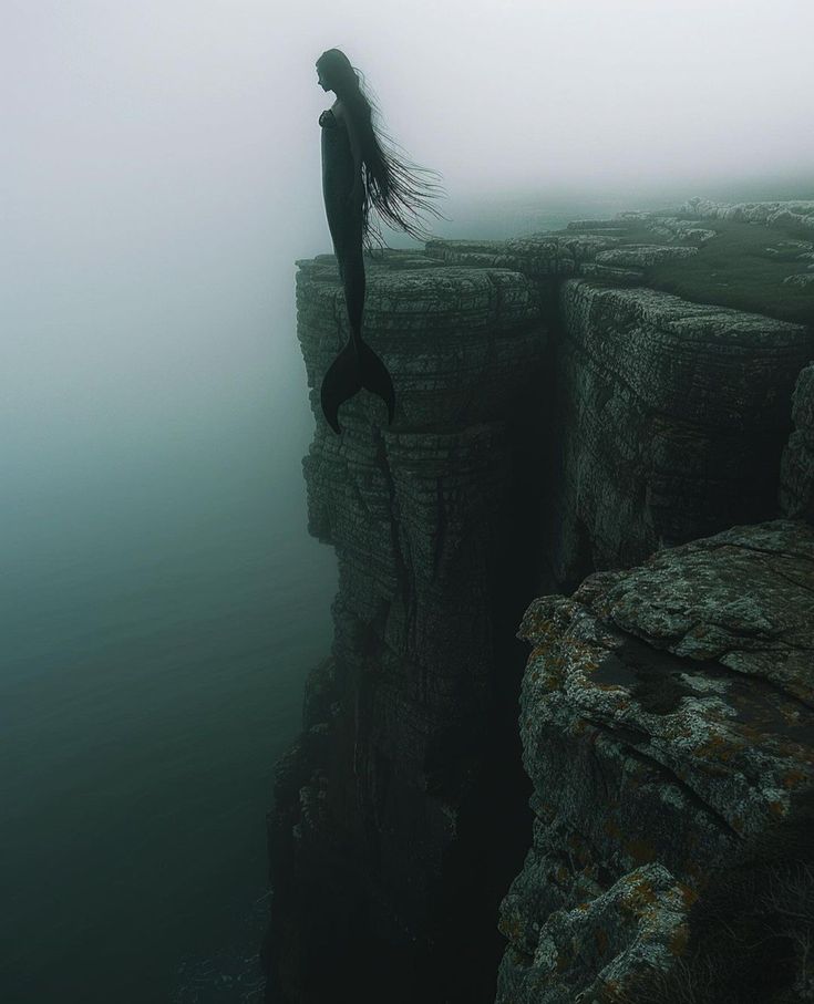 a woman standing on the edge of a cliff