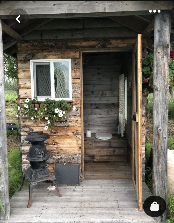 a small wooden cabin with a stove and potted plants on the outside porch area