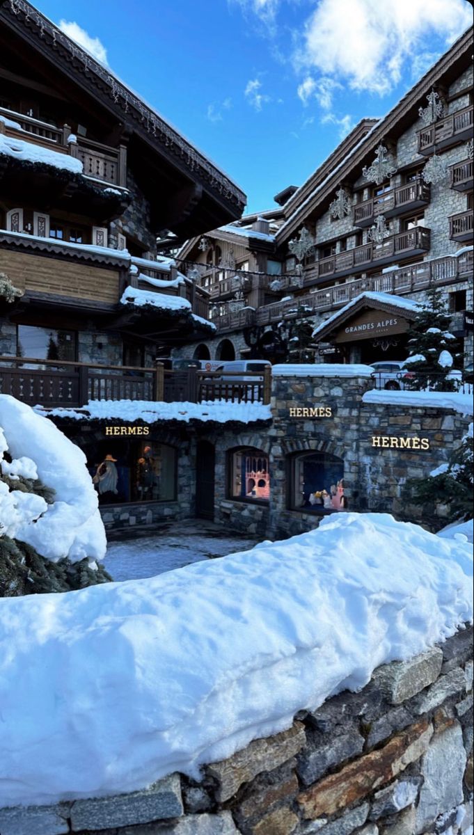 the snow is piled on top of the stone wall in front of an apartment building