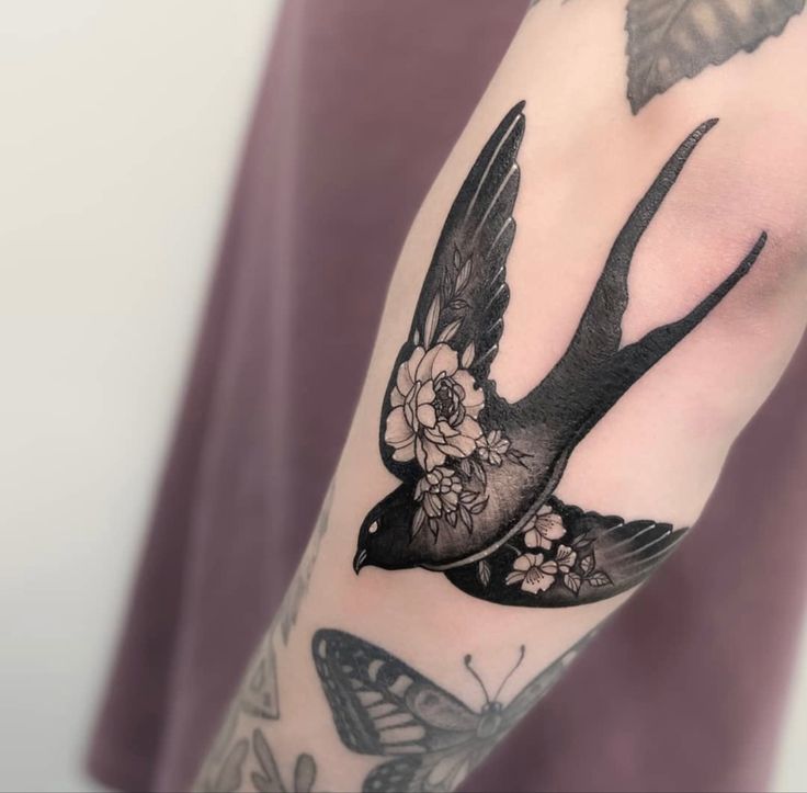 a black and white bird with flowers on it's arm