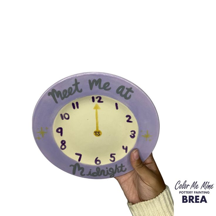 a hand holding up a purple clock with the words meet me at midnight on it