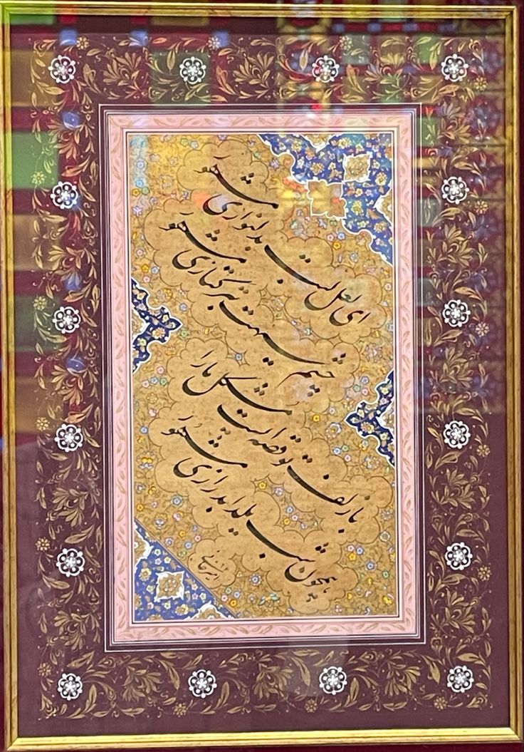 an arabic calligraphy in gold and blue with floral designs on the border, surrounded by flowers