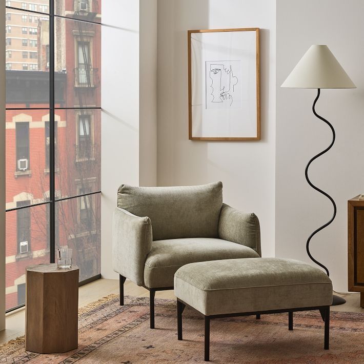 a living room with a chair and ottoman next to a large window overlooking the city