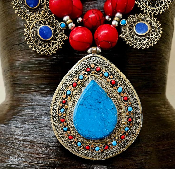 This stunning, jaw drop creation is from my private vault, and unworn. It is a big, bold, chunky and heavy beaded chest piece comprised of red, blue and green magnesite round beads with shiny silver tone metal balls. 12 lapis lazuli fancy filigree charms are suspended from the outer most strand and a blue and red inlaid stone pendant is the focal point (most likely red coral, turquoise, magnesite or howlite). The vintage pendant measures 4.5" x 3.25". Two ornate gold tone strand separators are o Handmade Necklaces For Festivals, Red Beaded Necklace For Rituals, Red Pendant Beaded Necklace For Festivals, Traditional Gemstone Beads Necklace, Traditional Gemstone Bead Necklaces, Blue Necklace With Intricate Design For Festivals, Traditional Red Pendant Beaded Necklace, Traditional Beaded Necklaces With Natural Stones For Festival, Traditional Beaded Necklace With Large Pendant And Round Beads