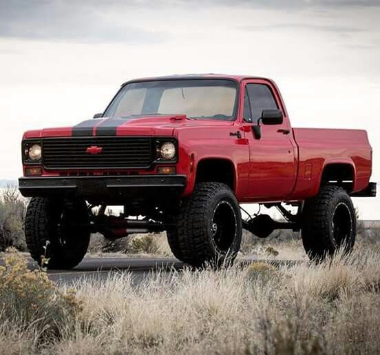 a red pick up truck parked on top of a field