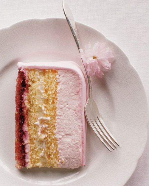 a piece of cake on a white plate with a fork and pink flower next to it