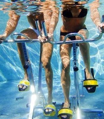 two women in bikinis are riding on a water scooter under the water