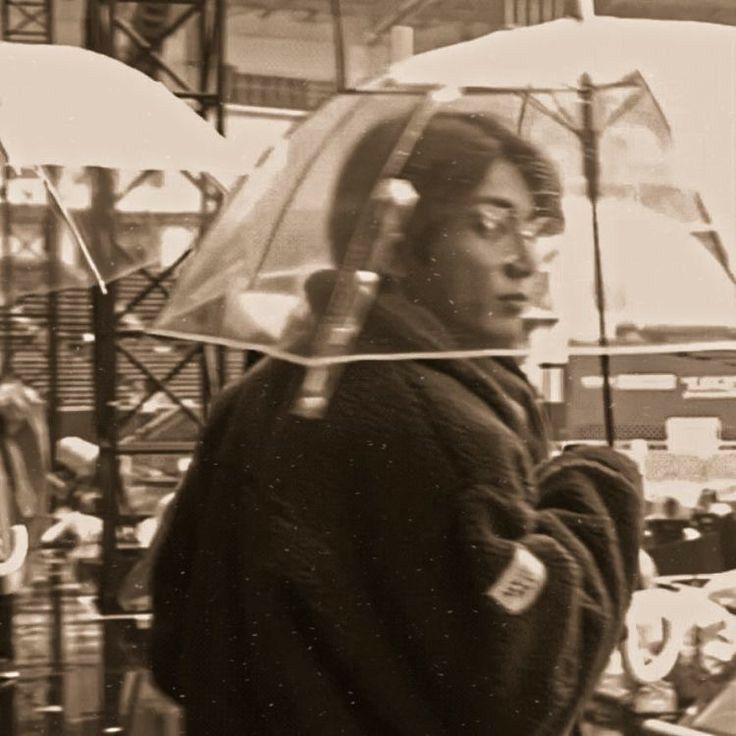 a man holding an umbrella while standing in front of a store filled with people and other items