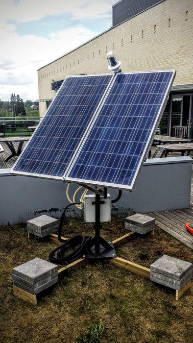 a solar panel sits on top of a roof in front of a building with other equipment