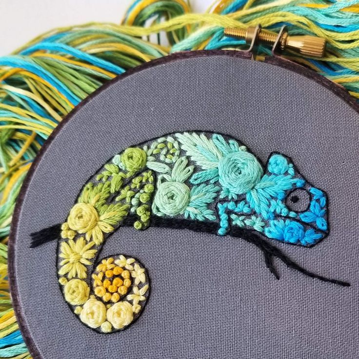 an embroidered chamelon sitting on top of some yarn