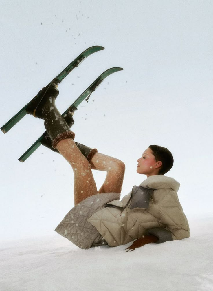 a man laying in the snow with skis on his feet and one leg up