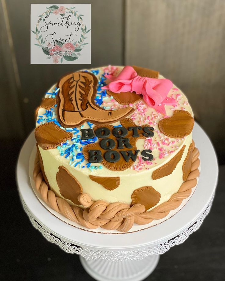 a birthday cake decorated with cowboy boots and pink bows on a white pedestal, sitting on top of a table