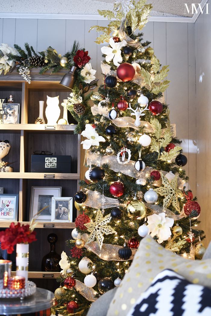 a decorated christmas tree in a living room with red, white and gold ornaments on it