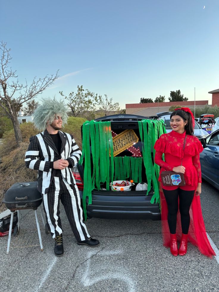 a man and woman dressed up in costumes standing next to a car with the back door open