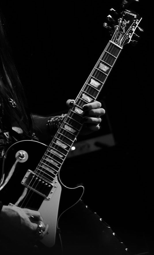 a man with long hair playing an electric guitar in black and white, on stage