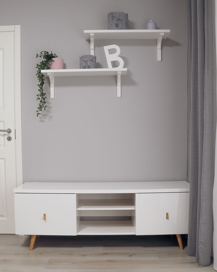 a white entertainment center with two shelves on each side and a plant in the corner