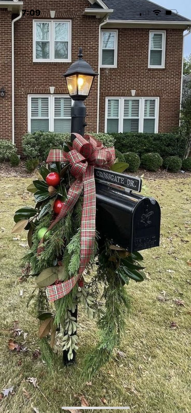 a mailbox decorated with greenery and bows in front of a house