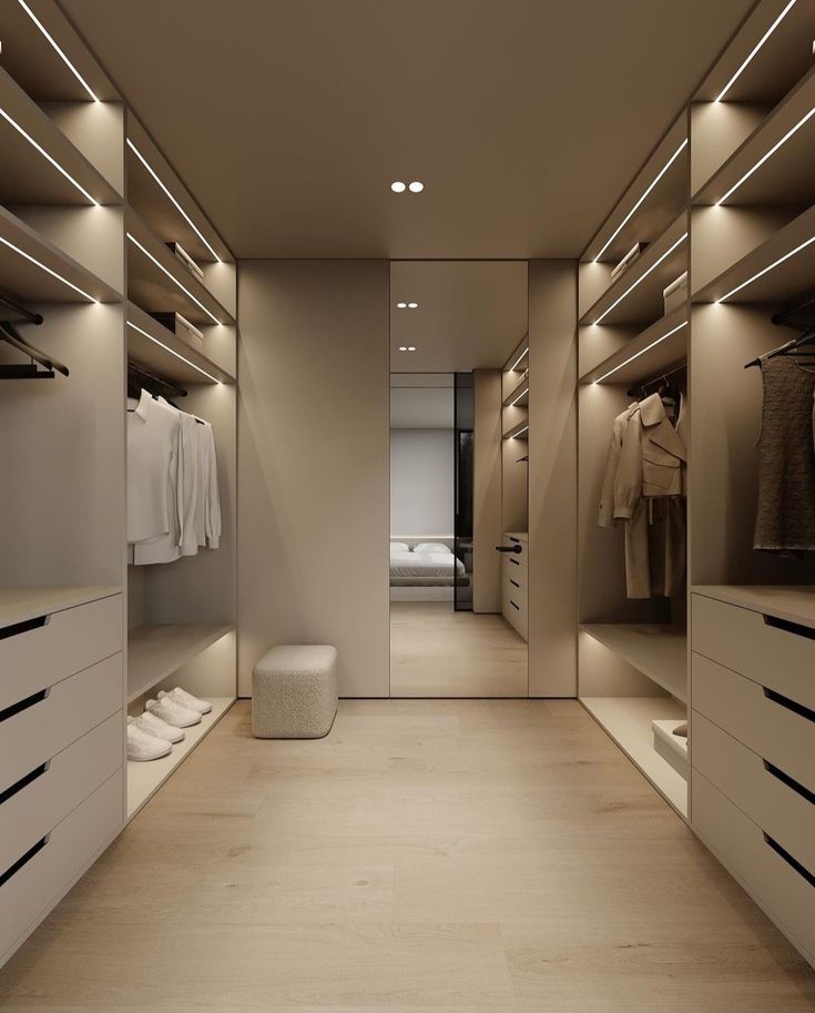 a walk in closet with white drawers and lights