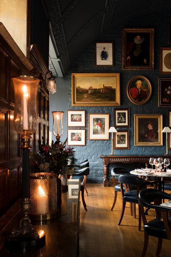 a dining room with blue walls and pictures on the wall above it's tables