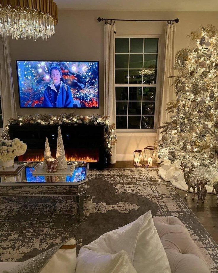 the living room is decorated for christmas with white and silver decorations, candles, and a large tv