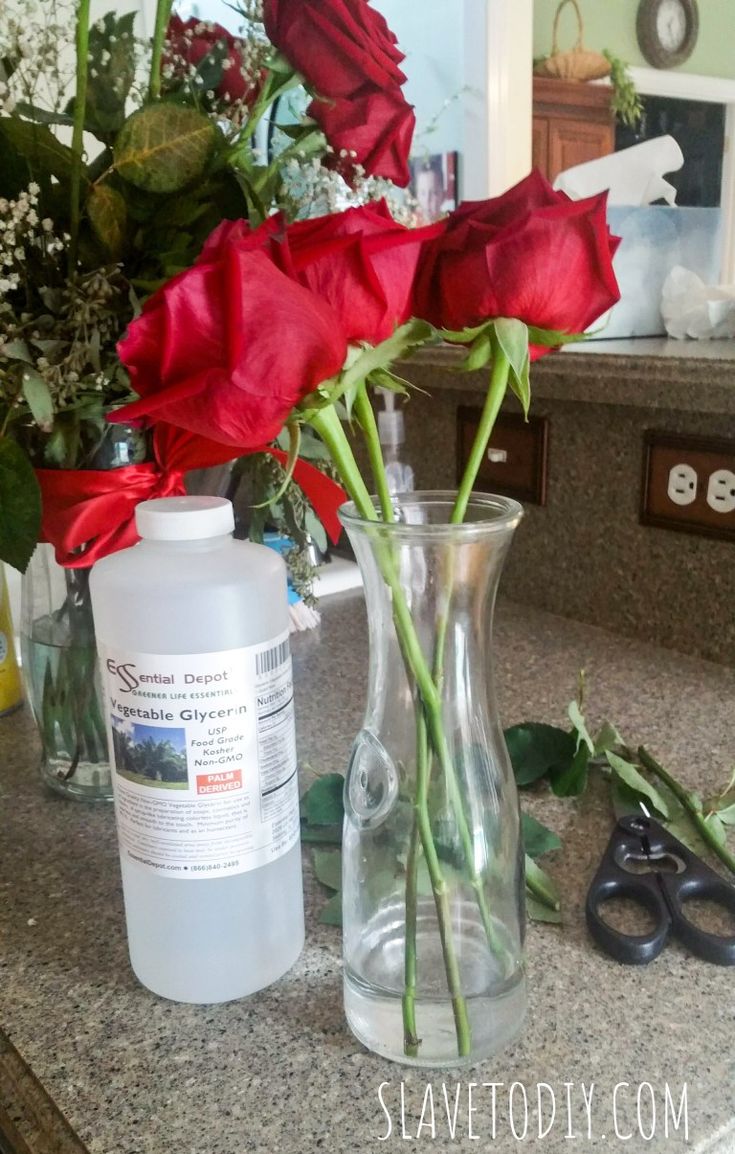 red roses in a clear vase on a counter top next to scissors and other flowers