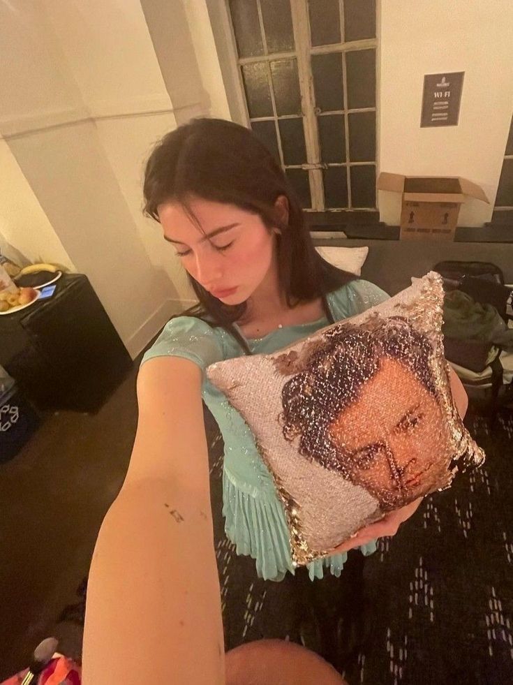 a woman sitting on the floor holding a pillow with an image of a man in it