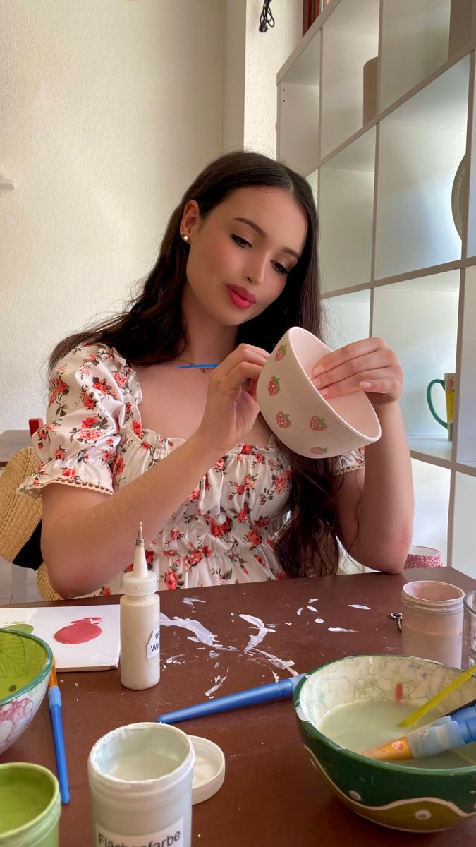 a woman sitting at a table holding a cup