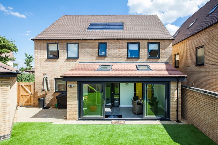 a house that has some grass in front of it and windows on the side of the house