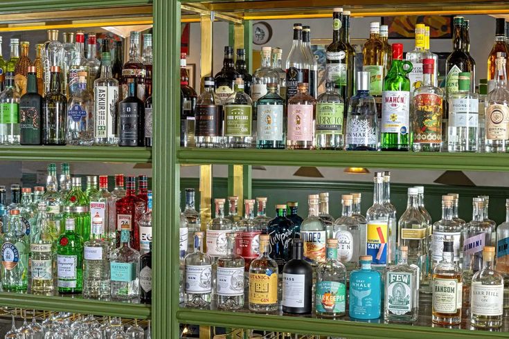 many bottles and glasses are lined up on the shelves