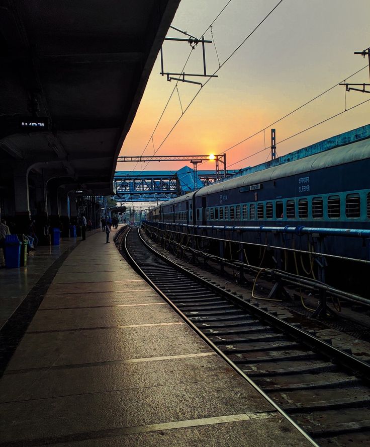 the sun is setting at an empty train station as people wait for their trains to arrive