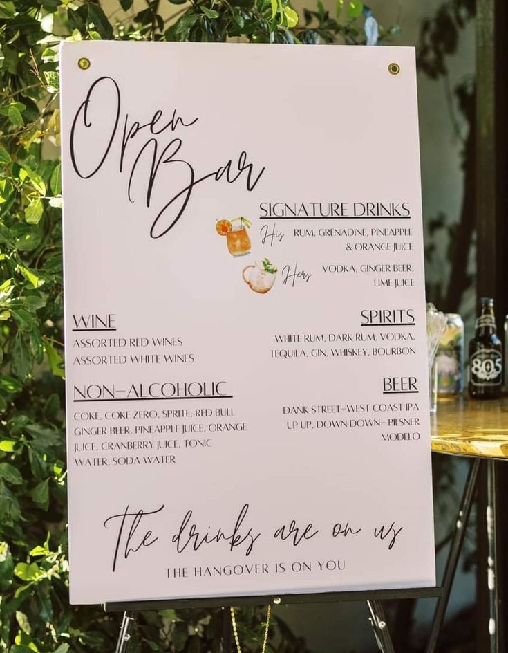 a sign with writing on it sitting next to a table in front of a tree