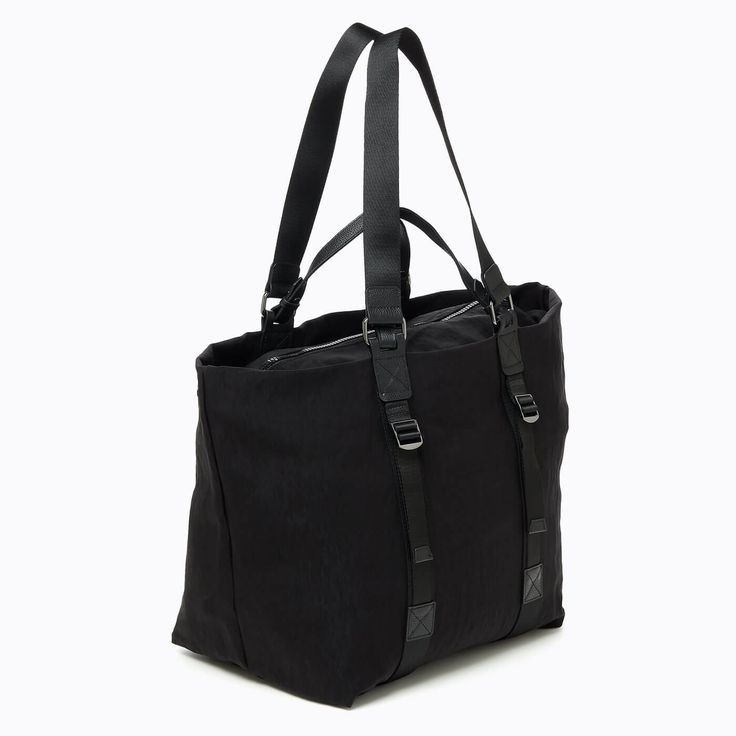 The Cali Large Tote is the ultimate work to weekend bag. This sleek nylon carry-all is perfectly sized for toting everything from your laptop to your favorite workout set for a lightweight commute to the office or your next gym class. Complete with an interior pocket and zip top, this spacious tote combines function with style. Details Nylon material with leather trim Gunmetal hardware Top zip closure Leather top handle and nylon webbed shoulder strap Interior slip pockets Unlined Measurements H Large Capacity Nylon Laptop Bag For On-the-go, Functional Black Travel Bag With Leather Handles, Everyday Leather Handle Tote Gym Bag, Black Nylon Weekender Bag With Large Capacity, Large Capacity Black Nylon Weekender Bag, Nylon Laptop Bag With Zipper Closure For Work, Nylon Laptop Bag With Zipper For Work, Modern Nylon Weekender Bag, Nylon Tote Shoulder Bag For Commuting