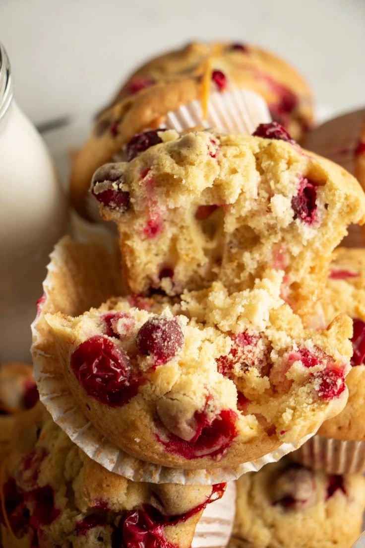 cranberry muffins stacked on top of each other next to a bottle of milk